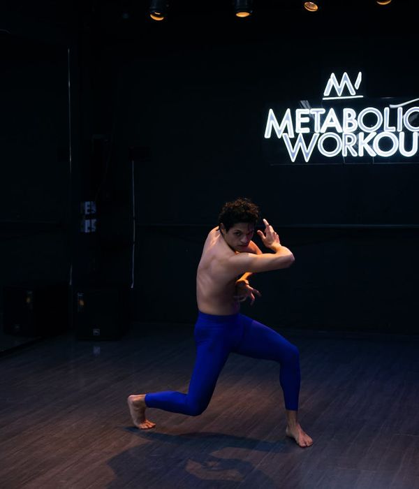 Man performing a dynamic stretching exercise in a modern studio.